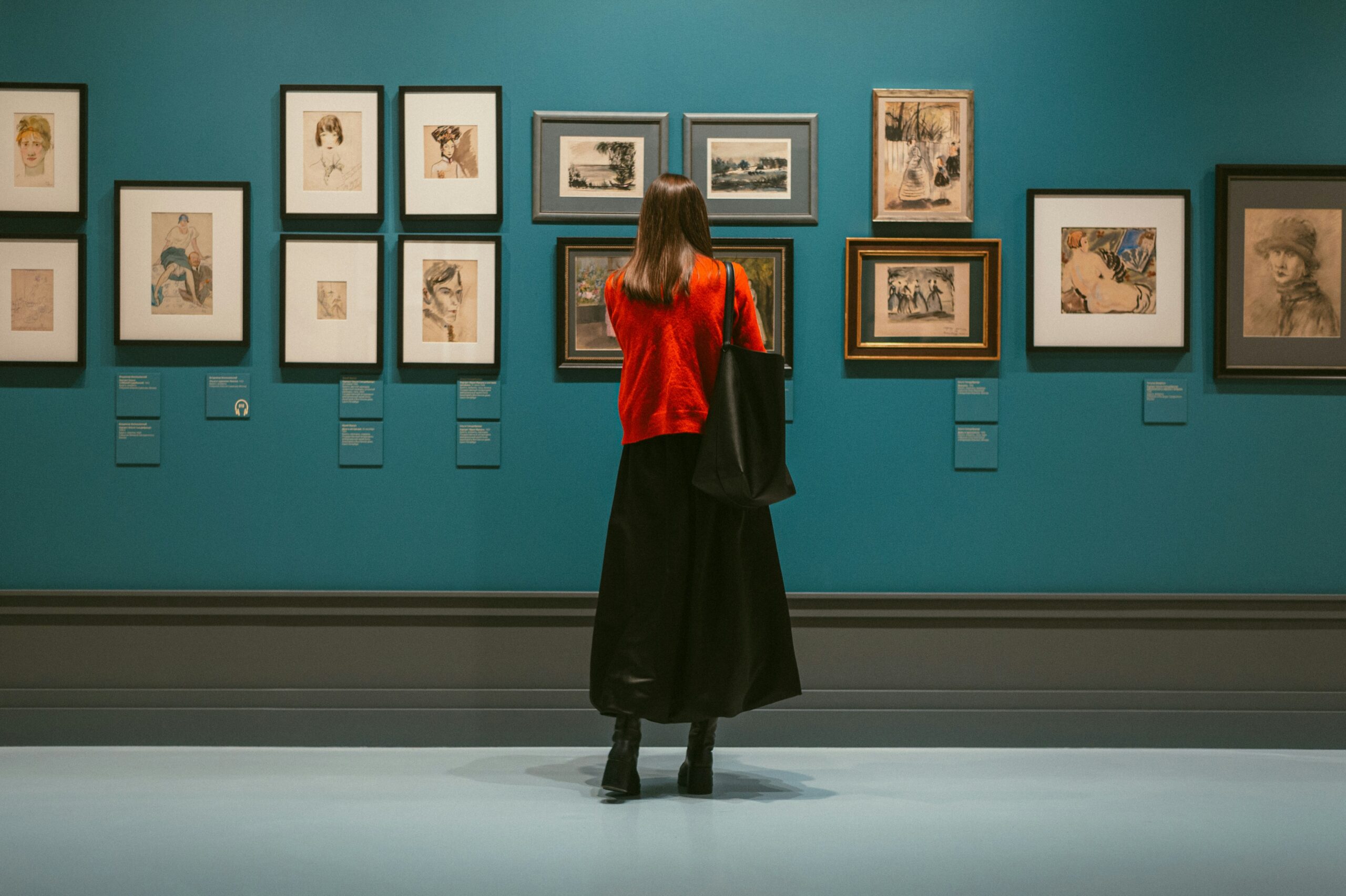 Woman in art gallery viewing art as women artists are breaking records in major auction sales.